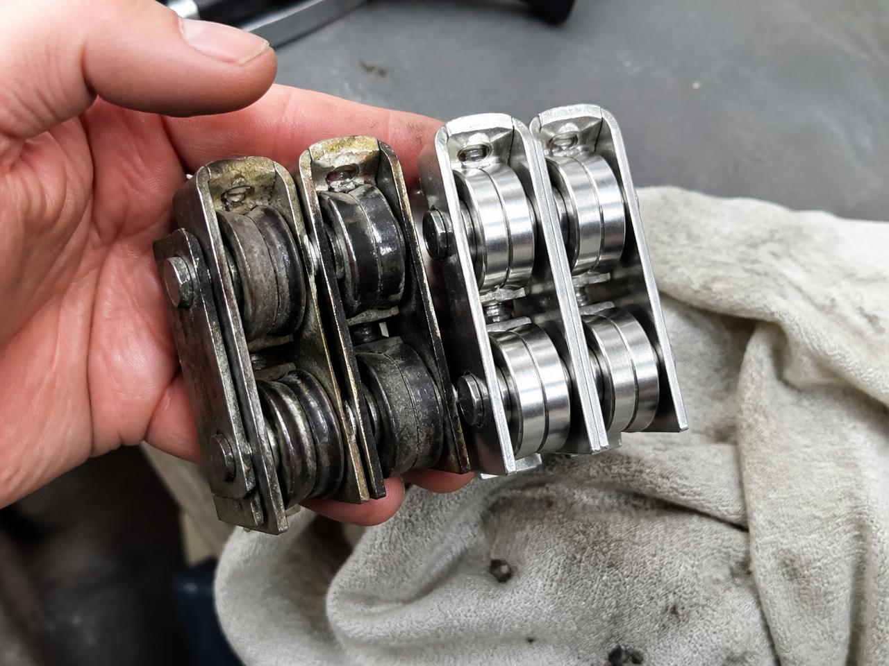 Worn sliding door rollers next to new stainless tandem roller assemblies